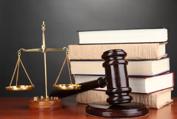 Wooden gavel, golden scales of justice and books on grey backgr